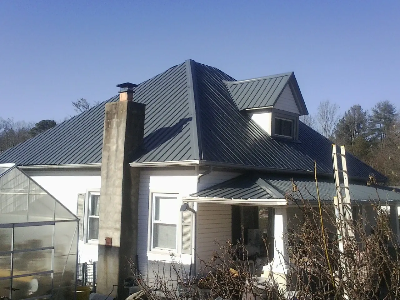 Dark blue standing seam metal roof on a white farmhouse with dormer — Slate & Tile Roof Repair by Roofing Brothers in Belle Vernon