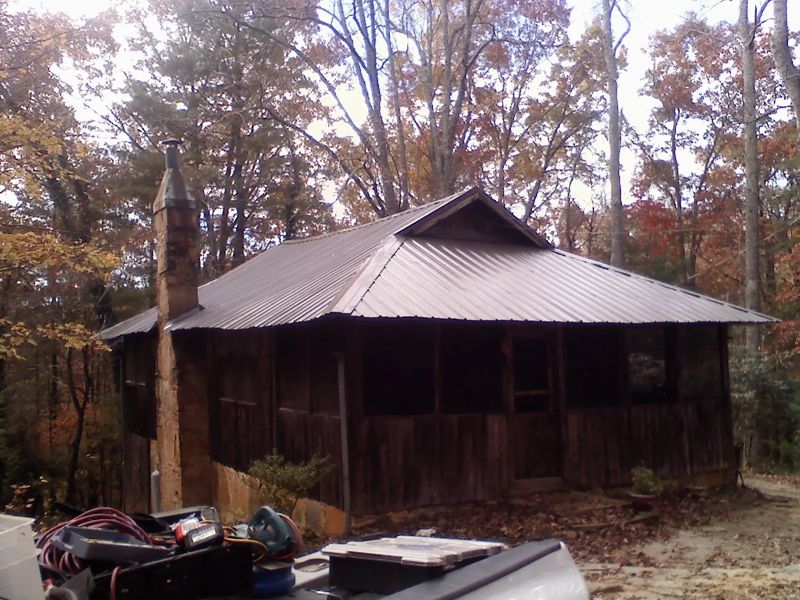 Brown metal hip roof on an old cabin with a stone chimney in Belle Vernon