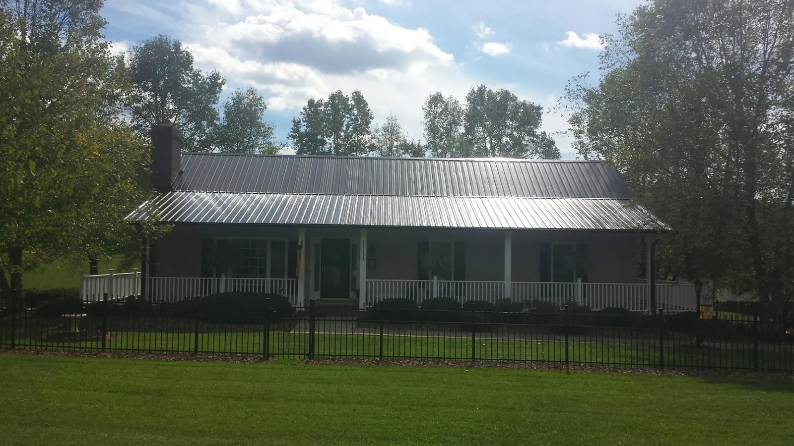 Gray metal roof on a brick ranch with a full width front porch — Gutter Guard Installation work by our crew in Belle Vernon