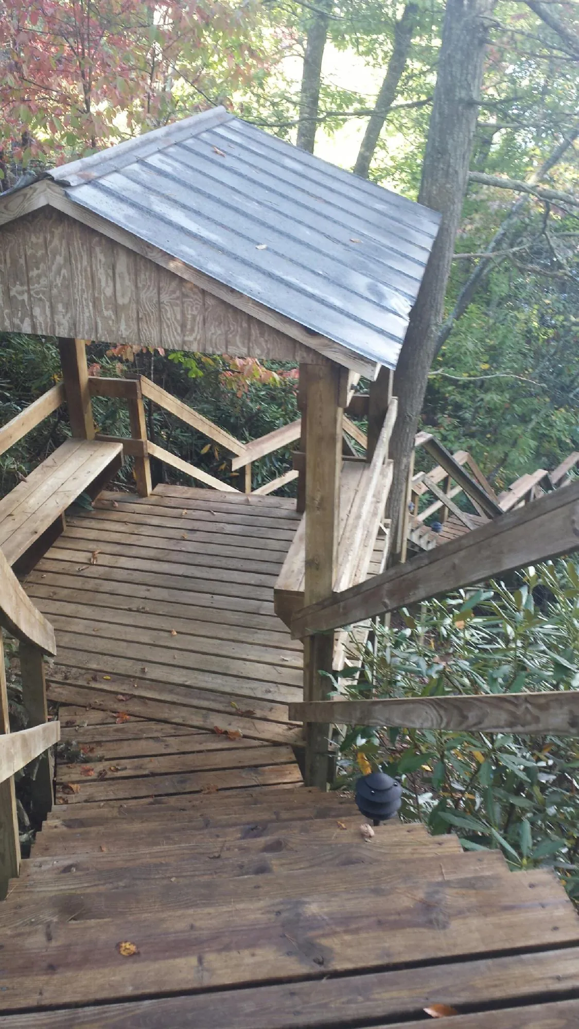 Metal roofed shelter over wooden steps on a wooded walkway — Skylight Repair & Installation work by our crew in Belle Vernon