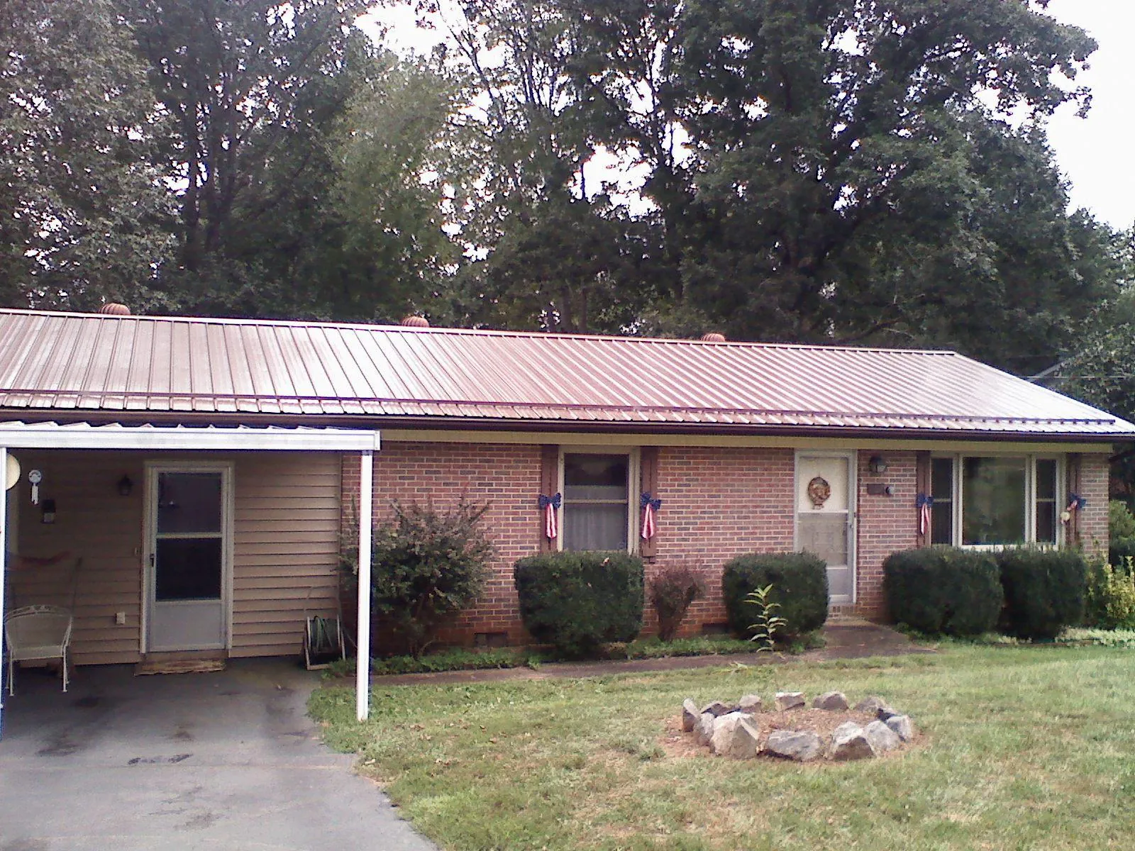 Bronze metal roof and carport on a brick ranch home — Roof Repair work by our crew in Belle Vernon