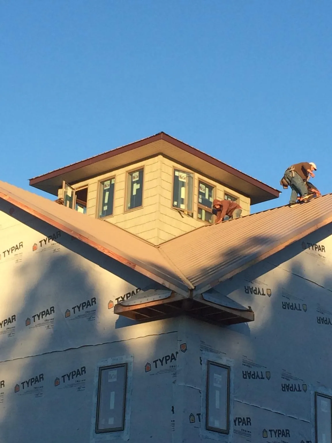 Roofers working around a rooftop cupola on a new metal roof at sunset — Roof Waterproofing in Belle Vernon by Roofing Brothers